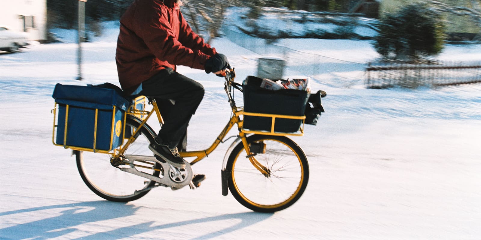 A rider pedaling a bicycle across a snow-covered street