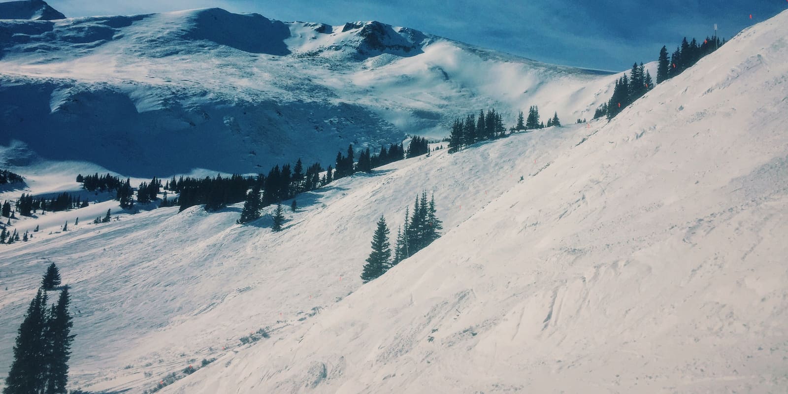 Wide snowy ski slope beneath a deep blue Colorado sky